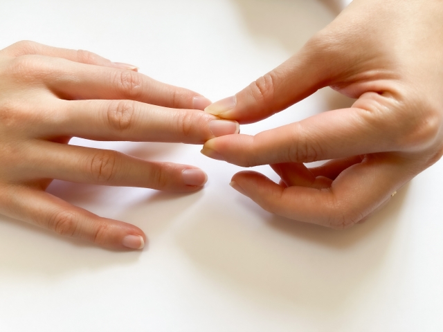 手の指のセルフマッサージをする女性