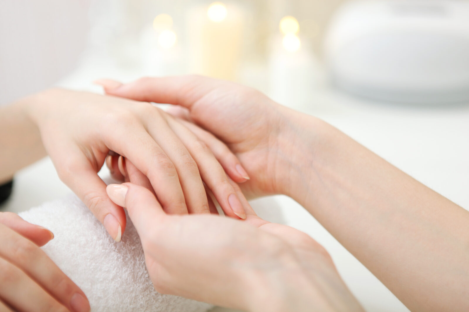 タオルの上でハンドマッサージを受ける女性の手元。やさしい圧で手をケアしている様子