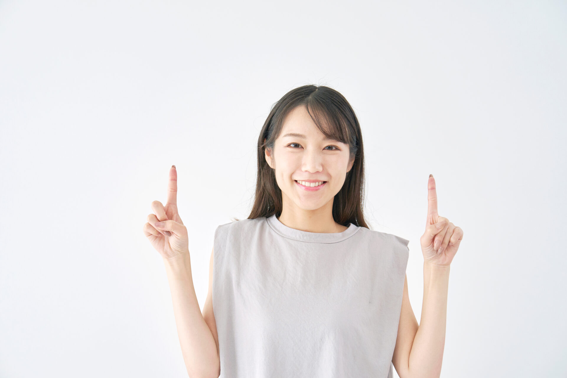 笑顔で両手の人差し指を上げ、「どちらが正解？」というイメージを表現する女性。